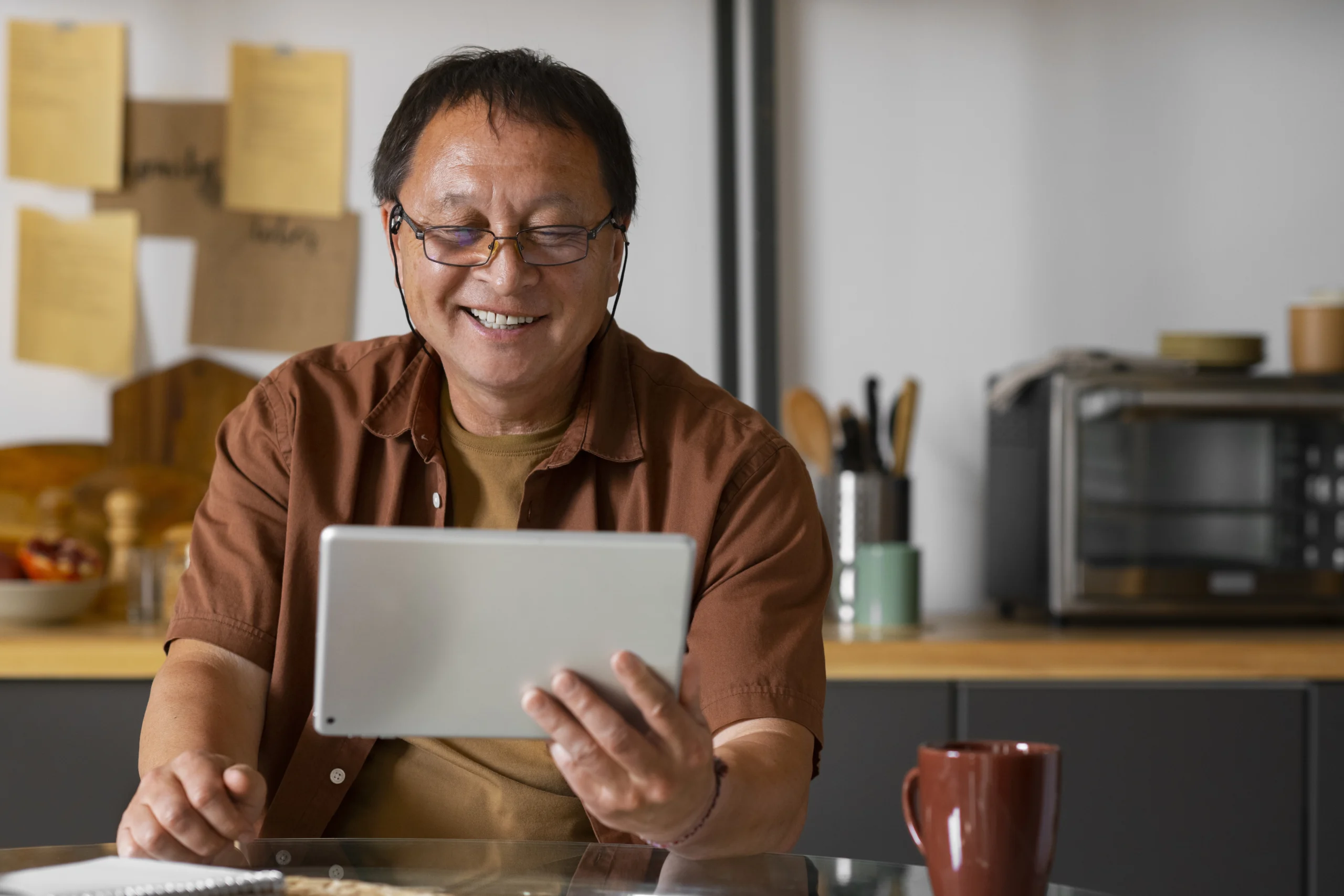 Pria paruh baya tersenyum sambil menggunakan tablet di rumah setelah mulai lebih peduli pada kesehatan.